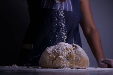 Kadın büyük bir ekmeğin üzerine un sürüyor.