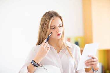 Düşünceli genç bayan beyaz kağıda not alıyor.