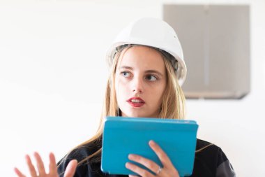 Beyaz şapkalı genç sarışın kadın teftiş sırasında tablet kullanıyor.