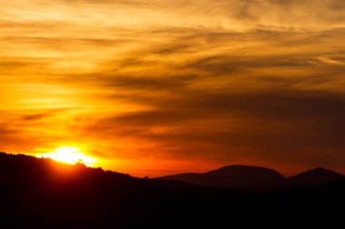 Güneş ve bulutlarla dağda gün batımı