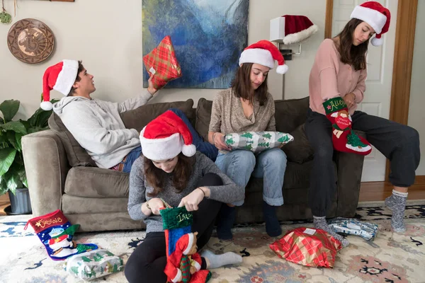 Three college-aged sisters and one\'s boyfriend in Santa hats pos