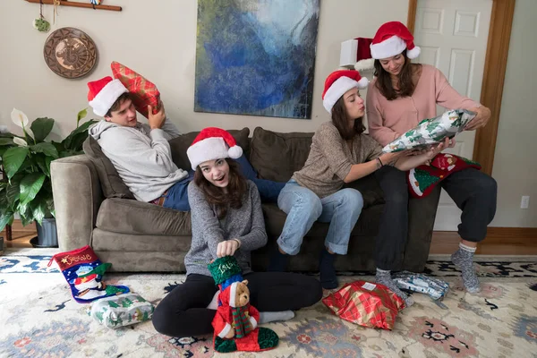 Four college-aged siblings wearing Santa hats open Christmas Gif