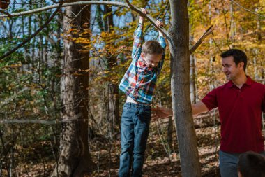 Genç baba ormanda çocuklarıyla oynuyor.