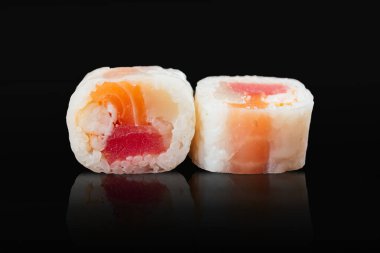 Japon suşisi siyah bir arkaplanda yuvarlanıyor.