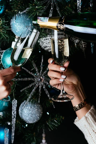 Vrouwen Handen Houden Champagne Glazen Achtergrond Van Een Kerstboom — Stockfoto