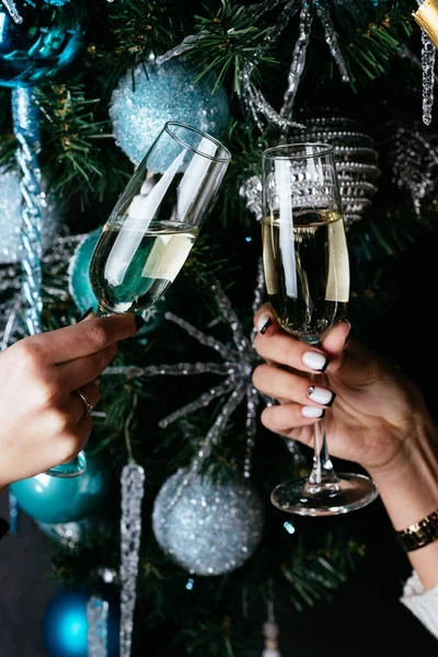 女人的手拿着香槟酒杯在圣诞树下 — 图库照片