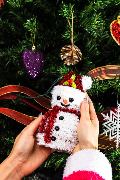 手はクリスマスツリーの前でクリスマスの雪だるまの置物を保持します 孤立したモミの木を飾る — ストック写真