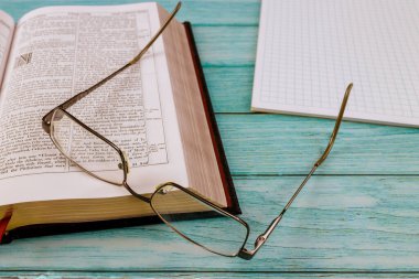 Masa masası İncil 'i açtı. Gözlüklerin üzerindeki dua zamanını kapat.