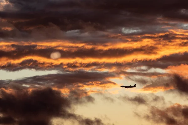 日落时 一架商业航空公司的飞机从云中降落 — 图库照片