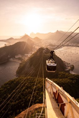 Sugar Loaf dağından Rio de Janeiro, Brezilya 'daki tramvaya, şehre ve okyanusa güzel altın gün batımı manzarası