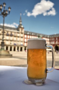 Madrid Plaza Belediye Başkanı Meydanı 'ndaki açık kafenin masasında beyaz köpüklü bir bardak taze soğuk bira servis ediliyor.