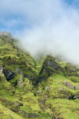 Düşük açılı sisli bulut uzak dağların yamaçlarında süzülüyor kayaların üzerinde çimlerle