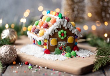 Şekerle süslenmiş zencefilli kurabiye evi ve şenlikli arka planda krema..