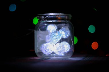Şeffaf kavanoz içinde kurşun ışıklar ve arka planda Bokeh ışıkları.