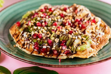 Pembe arka planda meyveli ve çikolatalı Belçika waffle 'ları.