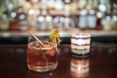 a glass of alcoholic drink with ice in the background