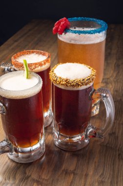 Michelada birası ahşap masada. Dört bira. Meksika içeceği.