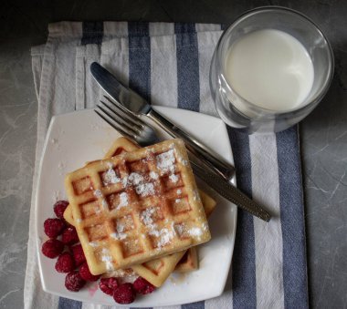 Masada çatal bıçaklı waffle ve süt manzarası var.