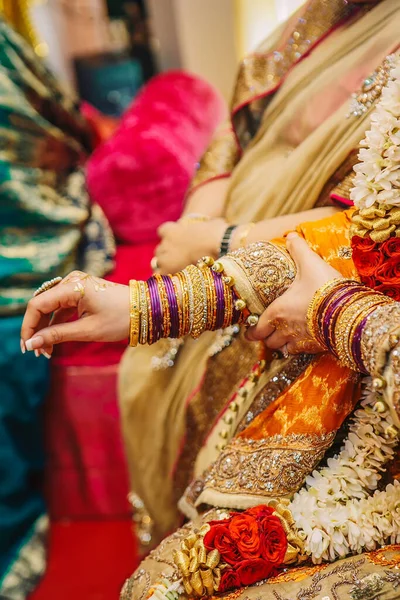 Indian pakistani bride hands with golden henna and bracelets