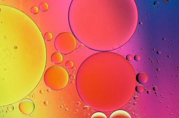Olive oil drops suspended in water with colorful backgrounds