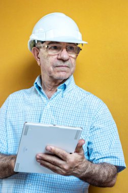 Elinde tablet tutan beyaz mühendis kasklı beyaz bir adam.