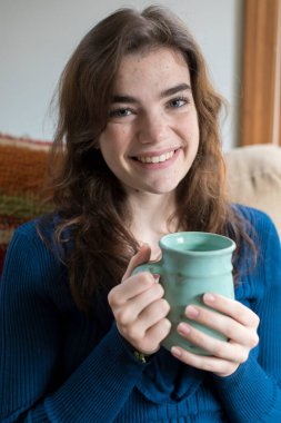 Portrait of seventeen year-old girl smiling and holding coffee cup