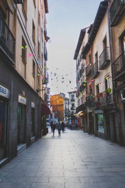 Madrid 'de renkli bayrakları olan bir sokak ve Latin' in yanında yürüyen insanlar.