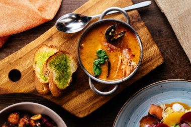 Tropikal yapraklarla süslenmiş karidesli deniz ürünleri kremalı çorba. Siyah plakalı, siyah arka planda. Üst görünüm, alanı kopyala.