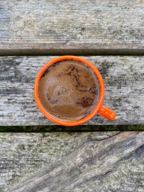 Tahta bir masanın üzerinde sade kahve olan turuncu fincan.
