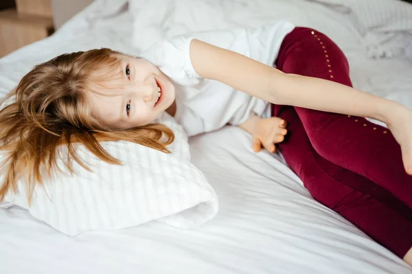 Klein Meisje Lacht Liggend Een Wit Bed — Stockfoto