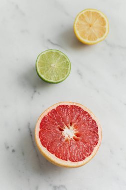 Taze narenciye, greyfurt, limon ve kireç, mermer arka planda kesilmiş.