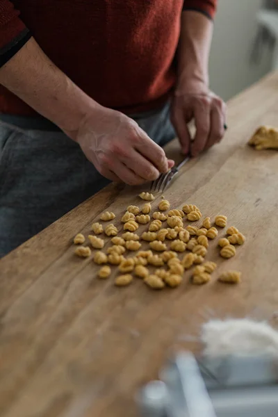 Close up of adult male's hands making pasta and gnocchi in moder