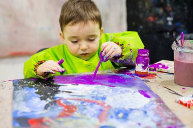 Toddler applying gouache paint with paintbrush during art activity