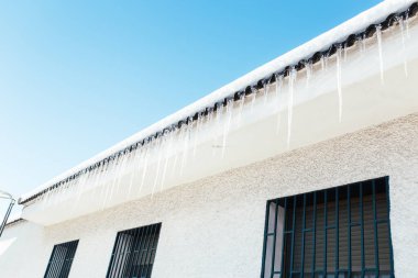 Çatıdan sarkan keskin buz saçakları. Buz sarkıtları