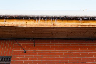 Çatıdan sarkan keskin buz saçakları. Buz sarkıtları