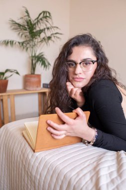 Genç kadın yatakta ders çalışıyor.