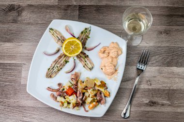 Aperatif olarak ahşap arka planda deniz ürünleri kadehi ve çatal bıçak.