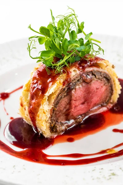 wellington beef with sauce on a plate on a white background