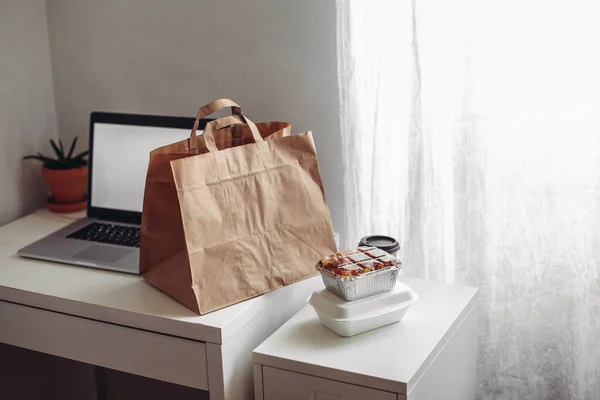 Take away boxes and cup, delivery bag, laptop on a white table