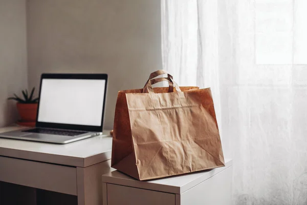 Craft delivery bag, laptop on a white table in a bright room