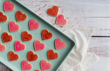 Beyaz ahşap üzerinde taze pişmiş kalp şeklinde kurabiyeler..