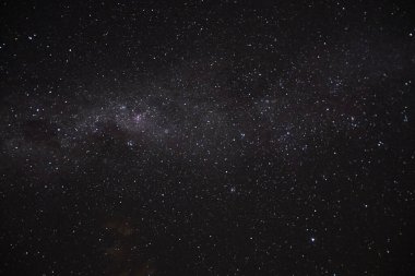 Yıldızlar ve samanyolu ve çevresel bulutsu ile karanlık gökyüzünün uzun bir görüntüsü.