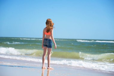 Kumsalda mayo giymiş genç kızıl saçlı kız..