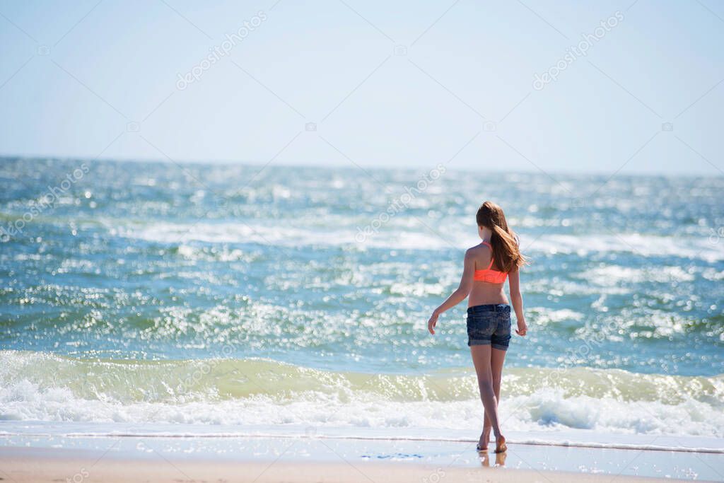 Tween red haired girl in swimsuit at the beach.