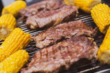 Biftek ve mısır koçanları ızgarada kızartılıyor.