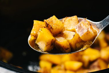 Patatesli fırında patates ve siyah arka planda baharat.