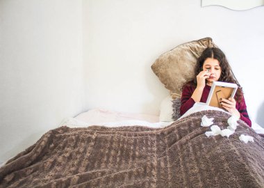 Genç bir kadın yatakta fotoğraf ve mendillerle ağlıyor.