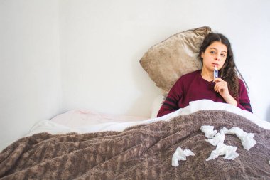 Yatağında termometresi olan hasta genç bir kadın.