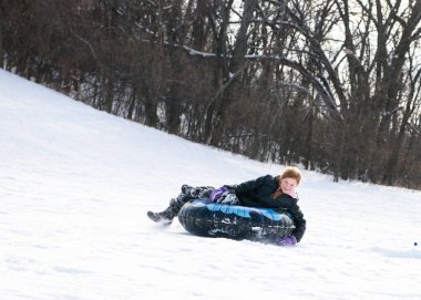 Aydınlık bir kış gününde kayak tepesinden kayan genç bir kız.