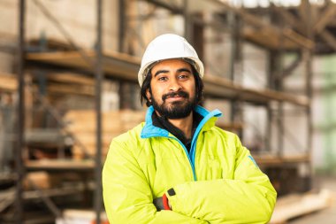 Depoda çalışan kasklı ve sakallı bir işçi.